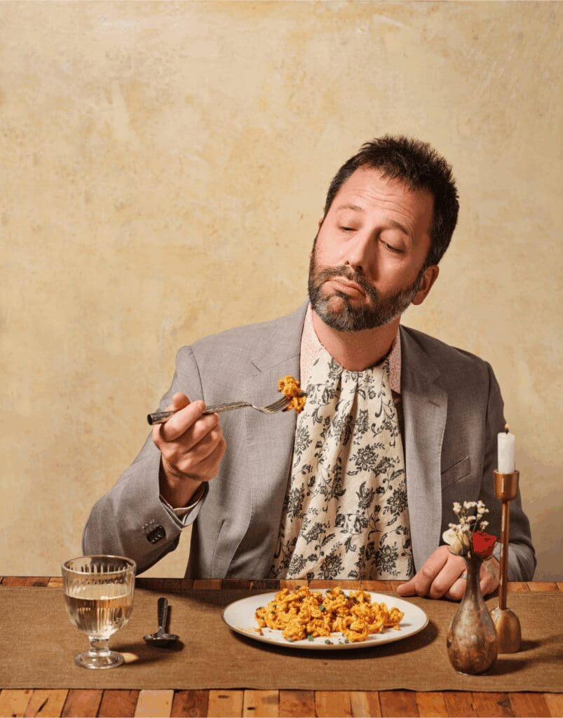 Dan Pashman sat at a table eating pasta with a fork 