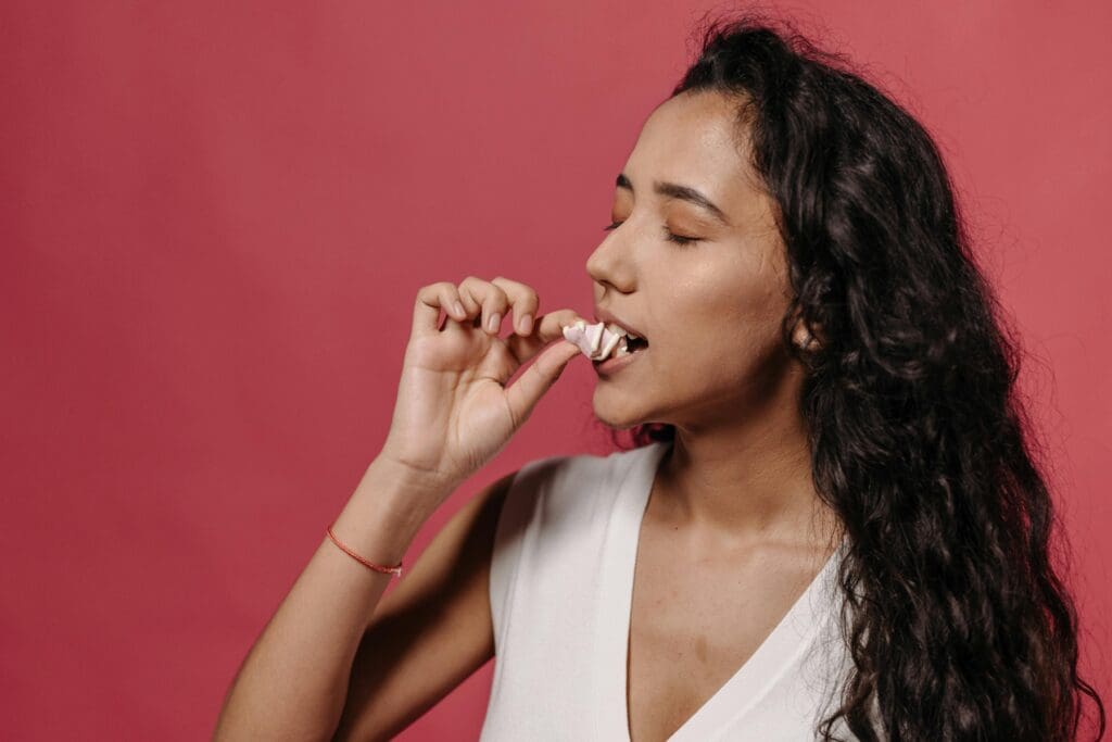 A woman biting into chewing gum.
