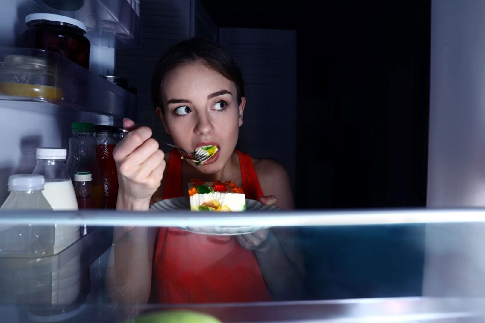 woman looking in fridge late at night