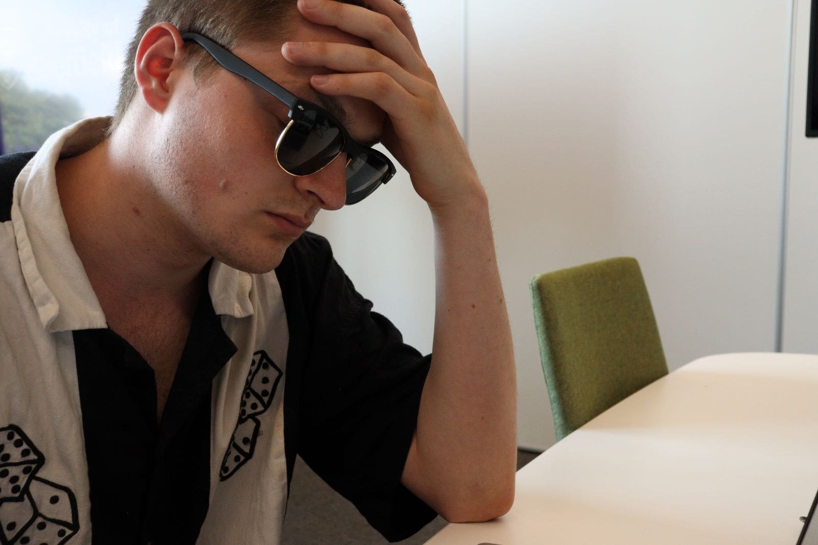 Hungover man sat at a table with hand on face