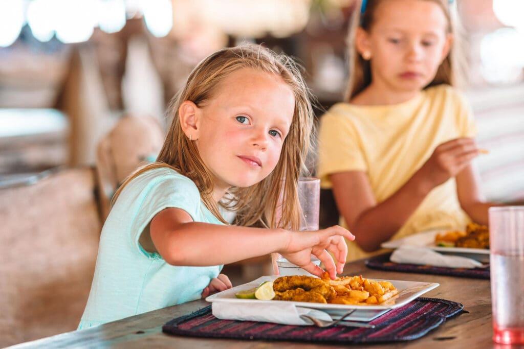 Girl eating chicken nuggets and chips.