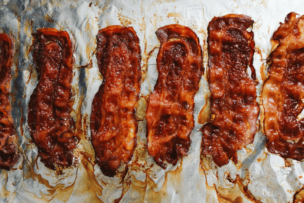 Strips of bacon lay across tin foil
