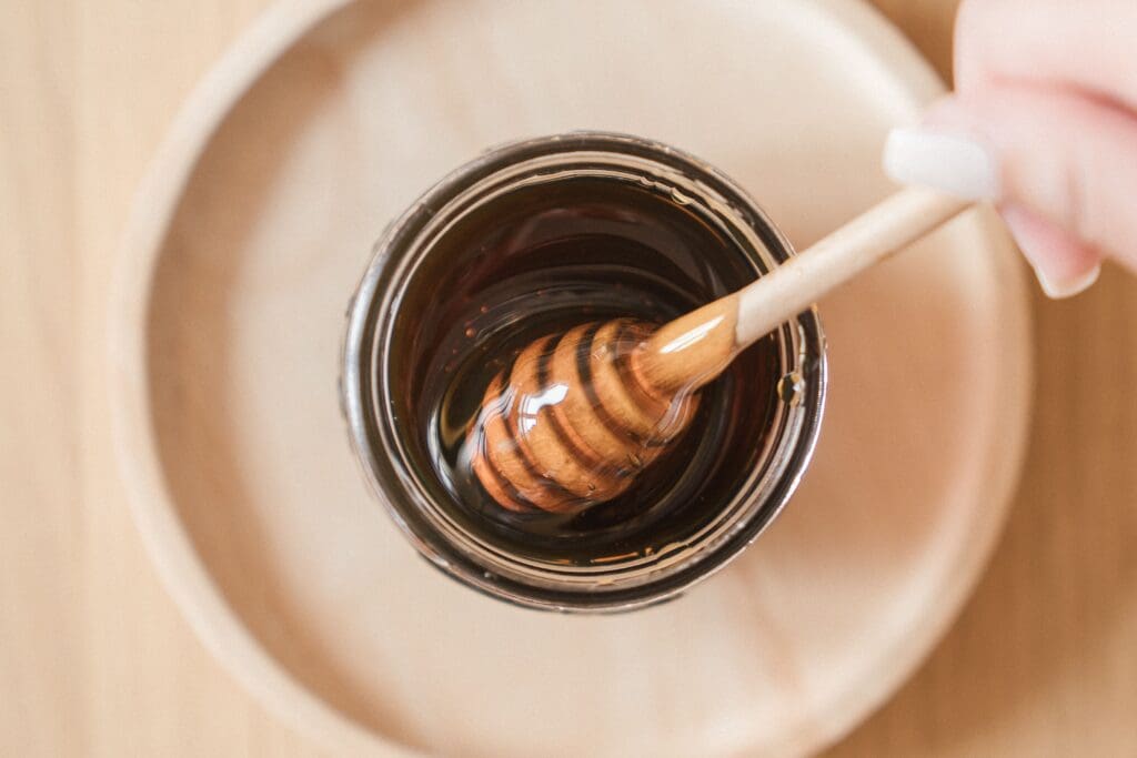 A honey stirrer in a jar of honey.